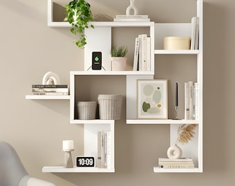 May include: A white, geometric wall shelf unit with multiple shelves, holding books, plants, and decorative items. A gray armchair sits in front of the shelf. A digital clock displays the time 10:09.