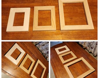 May include: Four wooden picture frames of varying sizes. The frames are all made of natural wood and have a simple, classic design. The frames are arranged in a row on a wooden surface.