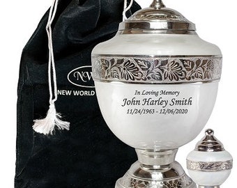May include: A white cremation urn with silver accents and a matching keepsake urn. The urn has a floral design and the inscription "In Loving Memory John Harley Smith 11/24/1963 - 12/06/2020". A black velvet bag is included.