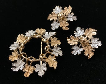 Op de afbeelding: Een set van drie bladvormige broche's in goud- en zilverkleur. De broche's zijn in de vorm van bladeren en zijn met elkaar verbonden om een cirkel te vormen. De broche's zijn in vintage stijl.