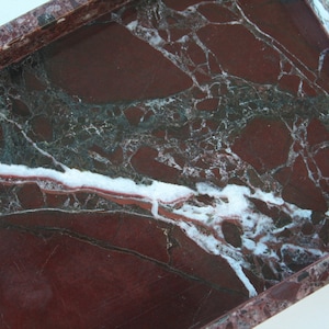 May include: A rectangular marble tray with a red, white, and green marbled pattern. The tray has a raised edge.