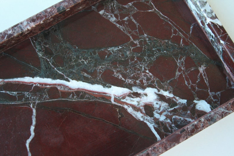 May include: A rectangular marble tray with a red, white, and green marbled pattern. The tray has a raised edge.