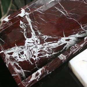 May include: A rectangular tray made of red marble with white veining. The tray has a raised edge and is perfect for serving or displaying items.