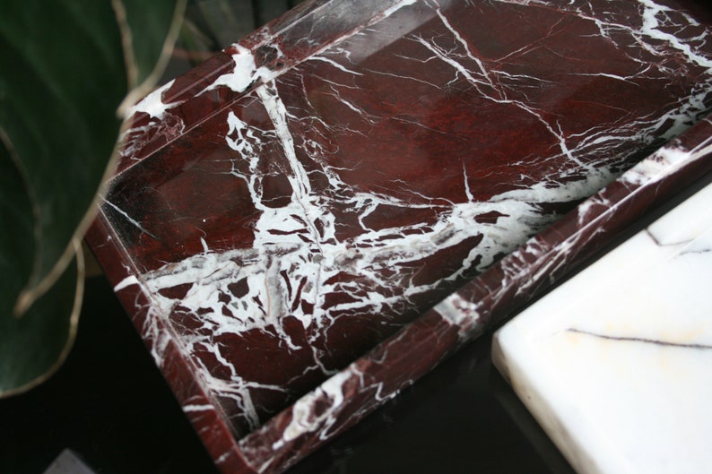 May include: A rectangular tray made of red marble with white veining. The tray has a raised edge and is perfect for serving or displaying items.
