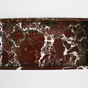 May include: A rectangular marble tray with a red and white marbled pattern. The tray has a raised rim.
