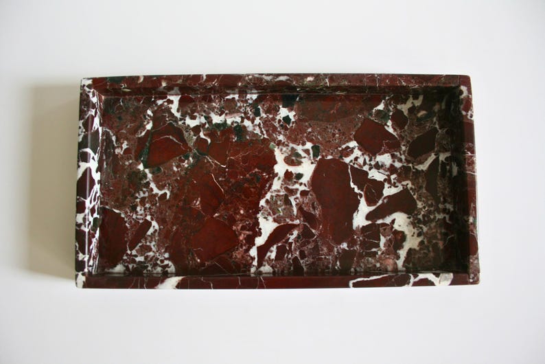 May include: A rectangular marble tray with a red and white marbled pattern. The tray has a raised rim.