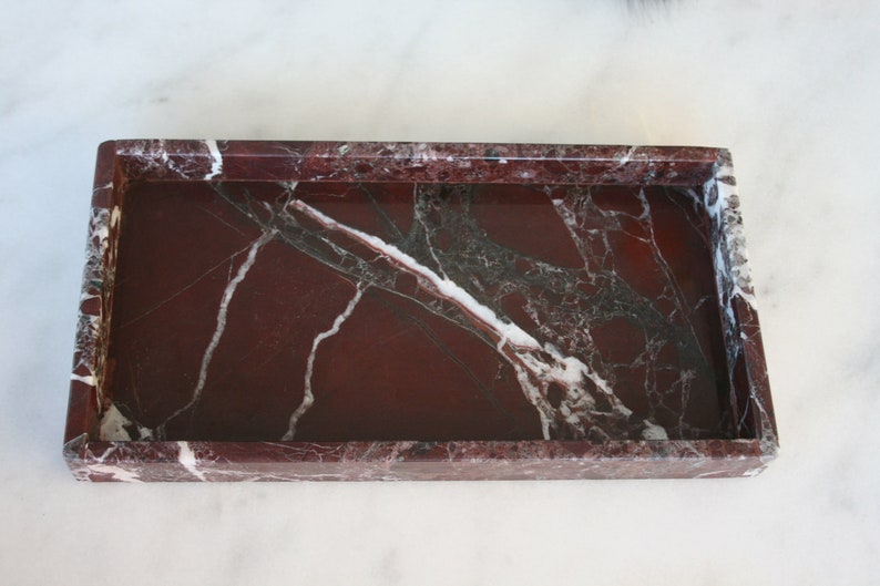 May include: A rectangular marble tray with a red, white, and black marbled pattern. The tray has a raised rim.