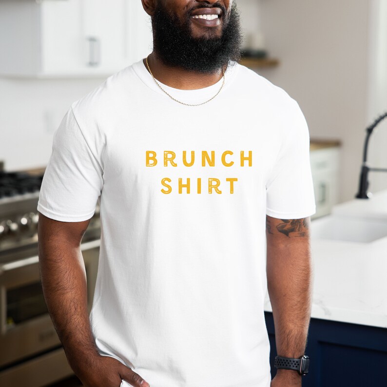 K&ouml;nnte beinhalten: Wei&szlig;es T-Shirt mit dem Aufdruck "BRUNCH SHIRT" in Gelb.