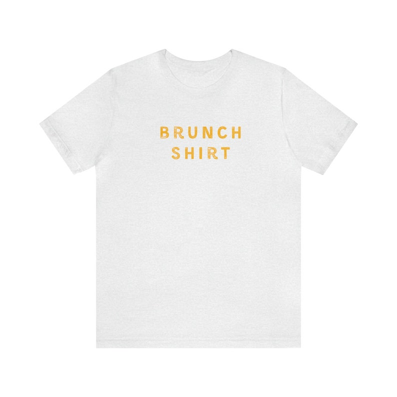 K&ouml;nnte beinhalten: Wei&szlig;es T-Shirt mit dem Aufdruck "BRUNCH SHIRT" in Orange.