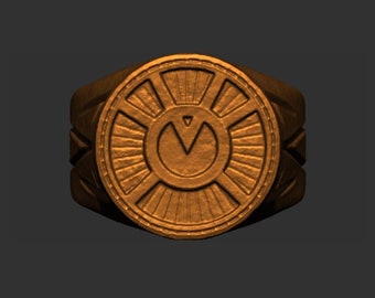 May include: A gold-colored ring with a circular design featuring a stylized sunburst and a symbol in the center. The ring is made of metal and has a textured surface.