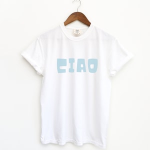 May include: White t-shirt with a light blue "CIAO" graphic printed on the front.