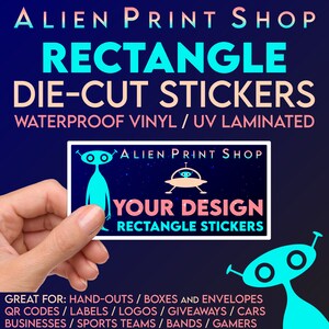 May include: A hand holds a blue and pink rectangle sticker with a cartoon alien and a UFO. The sticker says "Alien Print Shop" and "Your Design Rectangle Stickers".