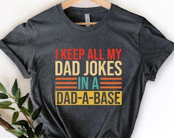 May include: A dark gray t-shirt with a vintage-style graphic that reads "I keep all my dad jokes in a dad-a-base".