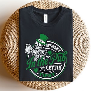 May include: Black t-shirt with a green graphic of a skeleton wearing a leprechaun hat and holding a beer mug. The graphic says "Everybody In the Pub Gettin' Tipsy".