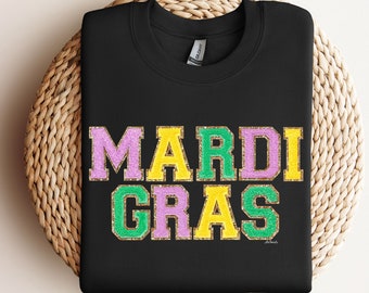 May include: Black t-shirt with the words "Mardi Gras" in green, purple, and gold glitter lettering.