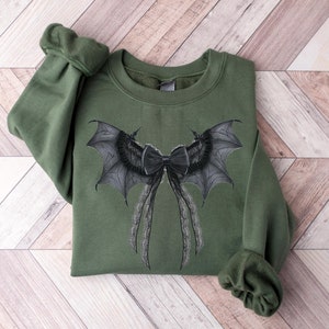 May include: A green sweatshirt with a black and gray bat wing bow design.