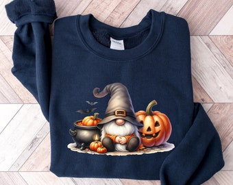 May include: A navy blue sweatshirt with a Halloween gnome design. The gnome is wearing a pointed hat and holding a cauldron with a pumpkin inside. There are two pumpkins and bats in the design.