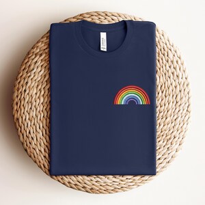 Op de afbeelding: Een marineblauw t-shirt met een geborduurde regenboog op de voorkant.