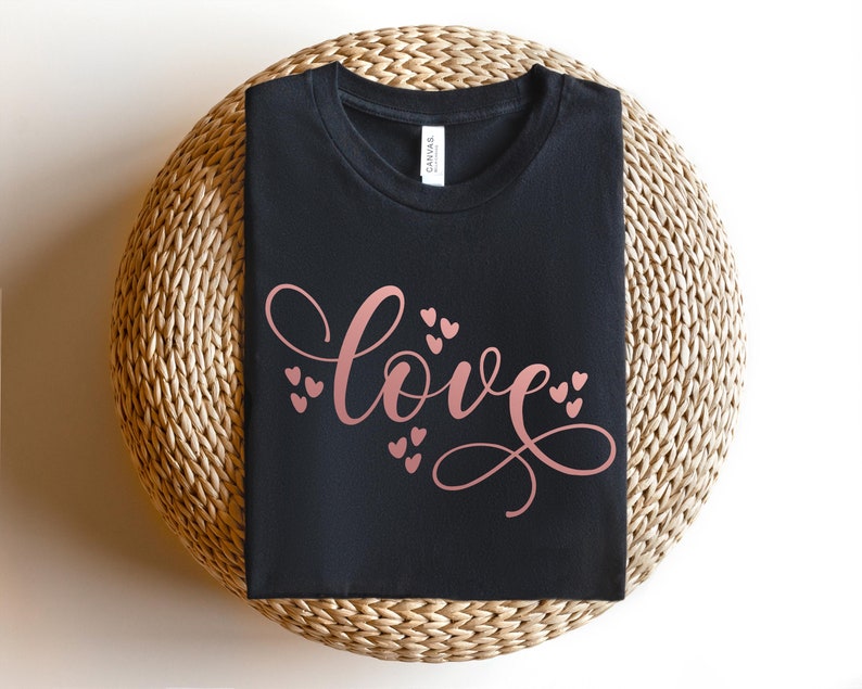 May include: A black t-shirt with the word "love" written in a cursive font in rose gold with small hearts surrounding the word.