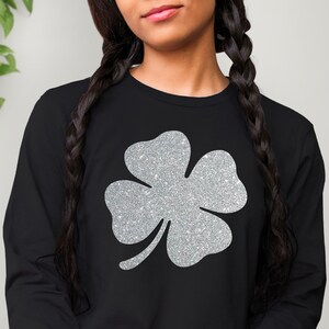 May include: Black long-sleeved shirt with a silver glitter four-leaf clover design.
