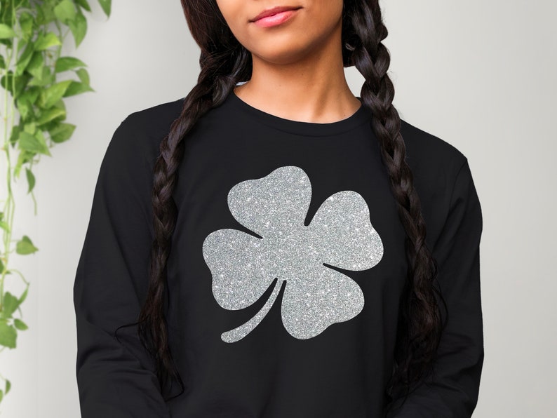 May include: Black long-sleeved shirt with a silver glitter four-leaf clover design.