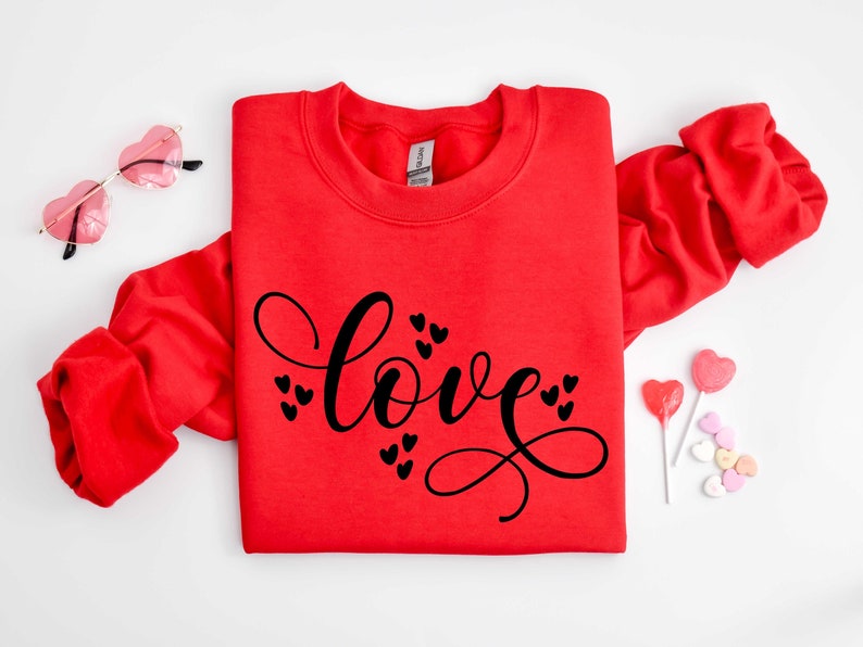 May include: Red sweatshirt with the word "love" written in black cursive script with small hearts surrounding the word.