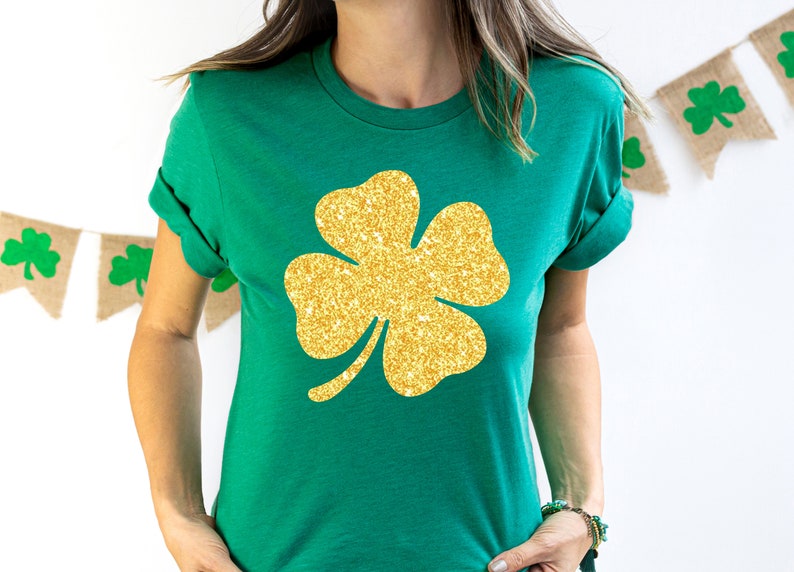 May include: A green t-shirt with a gold glitter four-leaf clover design.