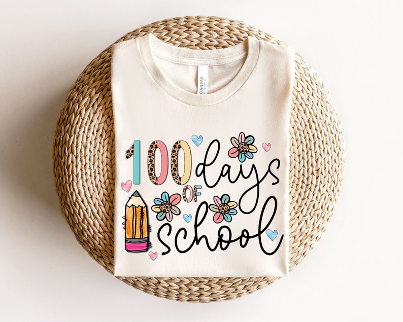 May include: A white t-shirt with the text '100 days of school' in black script. The number 100 is in colorful text with a leopard print pattern. The text is surrounded by colorful flowers and hearts.