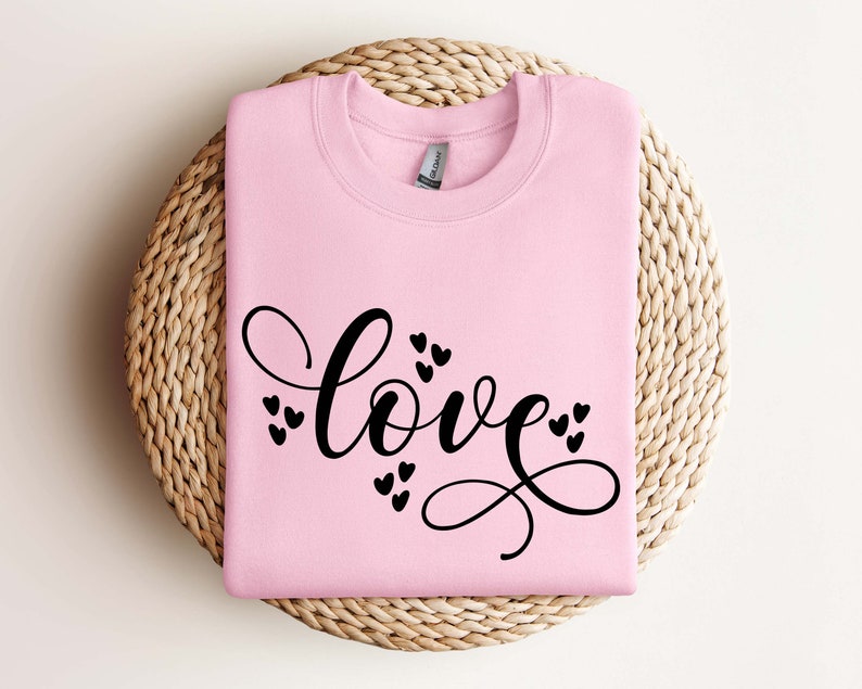 May include: Pink sweatshirt with the word "love" written in black cursive script with small hearts surrounding the word.