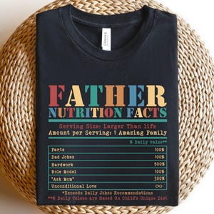 May include: Black t-shirt with a colorful graphic that reads "Father Nutrition Facts" with a humorous list of "nutritional" values like "Farts", "Dad Jokes", and "Unconditional Love".