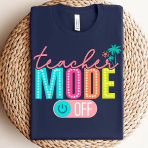 May include: A navy blue t-shirt with the text "teacher mode" in colorful letters with light bulbs around the words. The text "off" is on a pink and blue toggle switch.