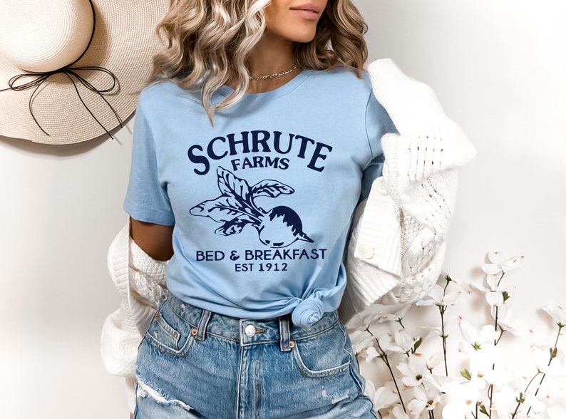May include: A light blue t-shirt with a navy blue graphic of a beet and the text "Schrute Farms Bed & Breakfast Est 1912".