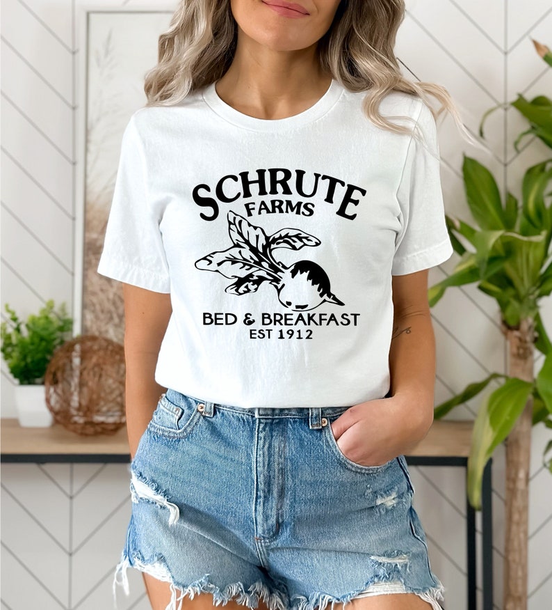 May include: White t-shirt with black text that reads "Schrute Farms Bed & Breakfast Est 1912" and a black graphic of a beet.