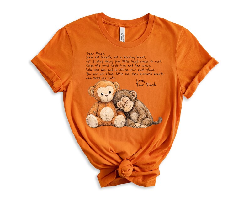 K&ouml;nnte beinhalten: Orangefarbenes T-Shirt mit einer Zeichnung von zwei Pl&uuml;schaffen. Einer ist braun und beige, der andere ist braun. Das Shirt hat handgeschriebenen Text, der lautet: "Dear Peach, I am not breath, art a beating heart...Love, Your Plush."