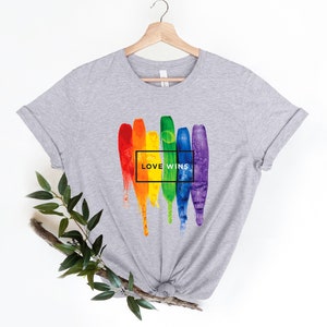 May include: Gray t-shirt with a rainbow paint splatter design and the text "LOVE WINS" in a black box.