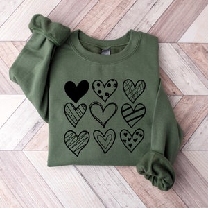 May include: A green sweatshirt with a black graphic of various hearts with different patterns.