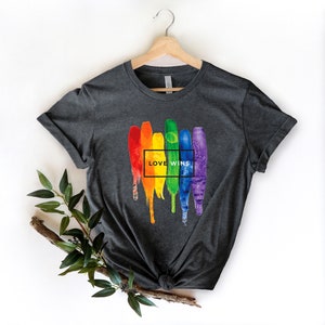 May include: A dark grey t-shirt with a rainbow paint splatter design and the text "LOVE WINS" in a white box.