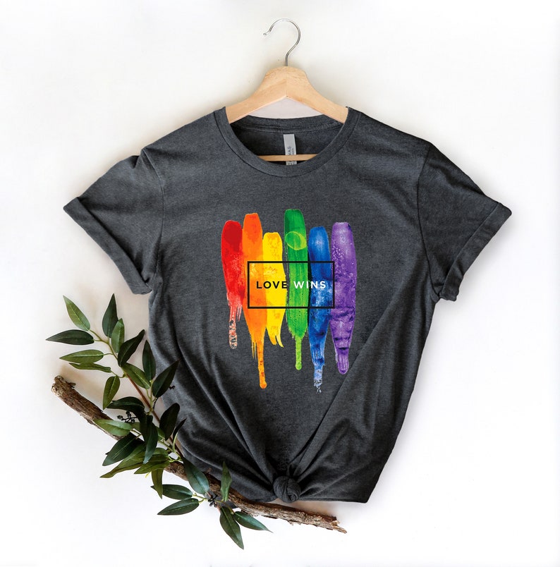 May include: A dark grey t-shirt with a rainbow paint splatter design and the text "LOVE WINS" in a white box.