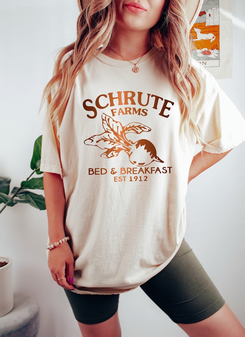 May include: A white t-shirt with a brown graphic of a beet and the text "Schrute Farms Bed & Breakfast Est 1912".