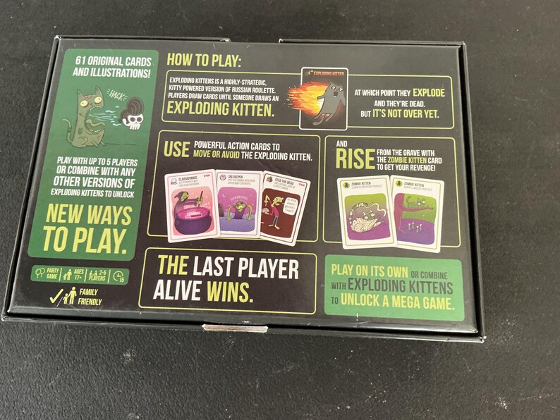 Może przedstawiać: Czarne pudełko do gry Exploding Kittens, z ilustracjami i tekstem. Pudełko zawiera instrukcje, przykłady kart i frazę &bdquo;Ostatni gracz, kt&oacute;ry przeżyje, wygrywa&rdquo;. Gra jest rodzinna i może być rozgrywana przez maksymalnie 5 graczy.