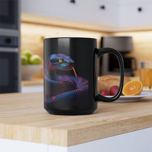 May include: Black coffee mug with a colorful snake design. The snake is blue, green, and red with yellow eyes. The mug has a white interior and a black handle.
