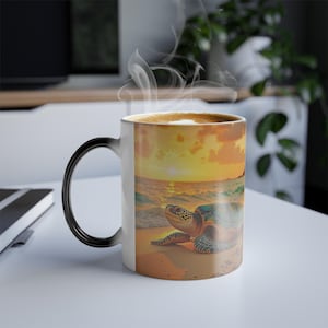 Puede incluir: Una taza de cambio de color negro y blanco con una tortuga marina en una playa al atardecer. La taza está llena de café y sale vapor de la parte superior.