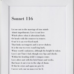 May include: A white framed print with a black and white text of Shakespeare's Sonnet 116. The text is centered on the page and the title "Sonnet 116" is at the top of the page. The print is sitting on a white surface with a vase of white flowers and two pens in a black pen holder.