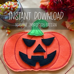May include: A felt orange pumpkin with a black stitched jack-o'-lantern face. The pumpkin is on a beige fabric background. The text "INSTANT DOWNLOAD MACHINE EMBROIDERY PATTERN" is above the pumpkin.