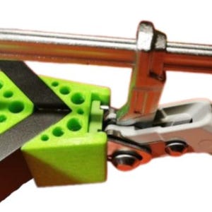 Peut inclure: Un serre-joint d'angle vert et noir avec une pince argentée attachée. Le serre-joint a une poignée blanche avec le texte "BESTTOOL" imprimé dessus.