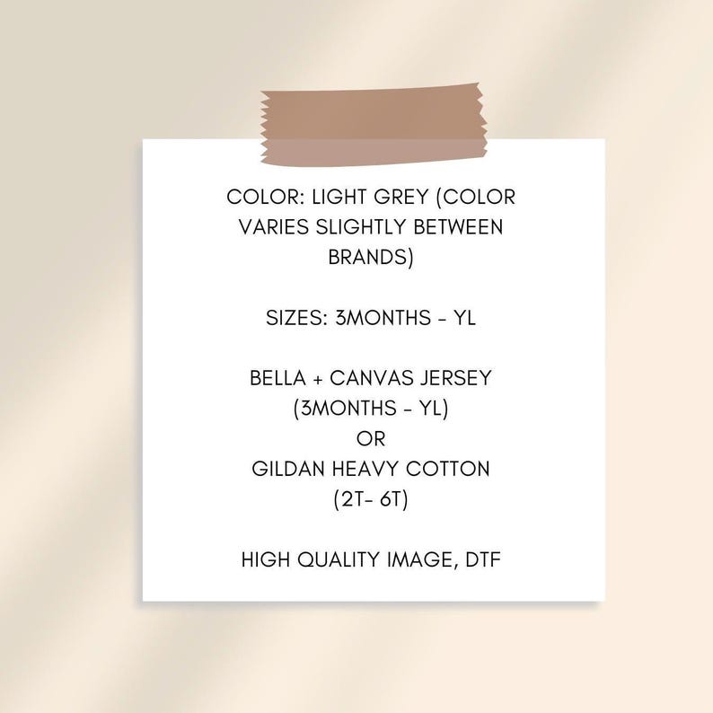 May include: A white paper with text about clothing sizes and materials, including "LIGHT GREY", "3MONTHS - YL", "BELLA + CANVAS JERSEY", and "GILDAN HEAVY COTTON". The paper is held by a piece of tape.