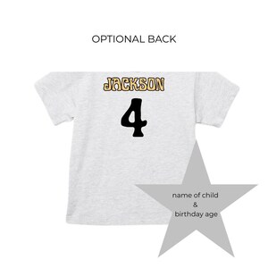 May include: A light gray t-shirt with the name "JACKSON" in a gold and black font above a large black number "4". The words "OPTIONAL BACK" are above the shirt. A gray star graphic is on the right.