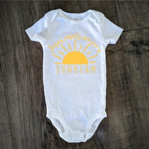 May include: White baby onesie with a yellow sun graphic and the text "Baby's wants me for a sunbeam".