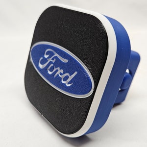 May include: A black and blue Ford hitch cover with a white trim. The Ford logo is in white on a blue oval.