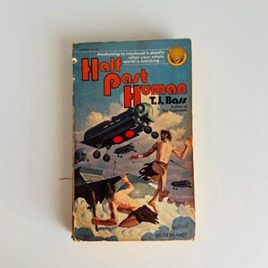Pu&ograve; includere: Libro tascabile vintage "Half Past Human" di T.J. Bass. La copertina presenta un'illustrazione fantascientifica con veicoli volanti e figure. Il titolo &egrave; in rosso su sfondo blu.